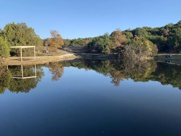 A serene lake with a wooden structure on the left, surrounded by trees and a clear sky. - Guest Home on Lake Godstone (Graford)