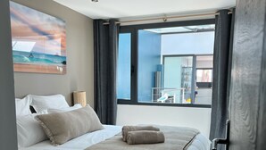 A modern bedroom with a large bed, a view of the outside, and a painting on the wall. - Villa Bord de mer - La Rochelle 8 /10 people - Swimming pool/Jacuzzi (Angoulins)