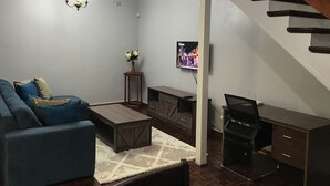 Ein modernes Wohnzimmer mit einer Couch, einem Couchtisch, einem Fernseher und einer Treppe.