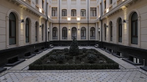 Une cour intérieure avec un jardin central, une architecture symétrique et des fenêtres disposées à intervalles réguliers.