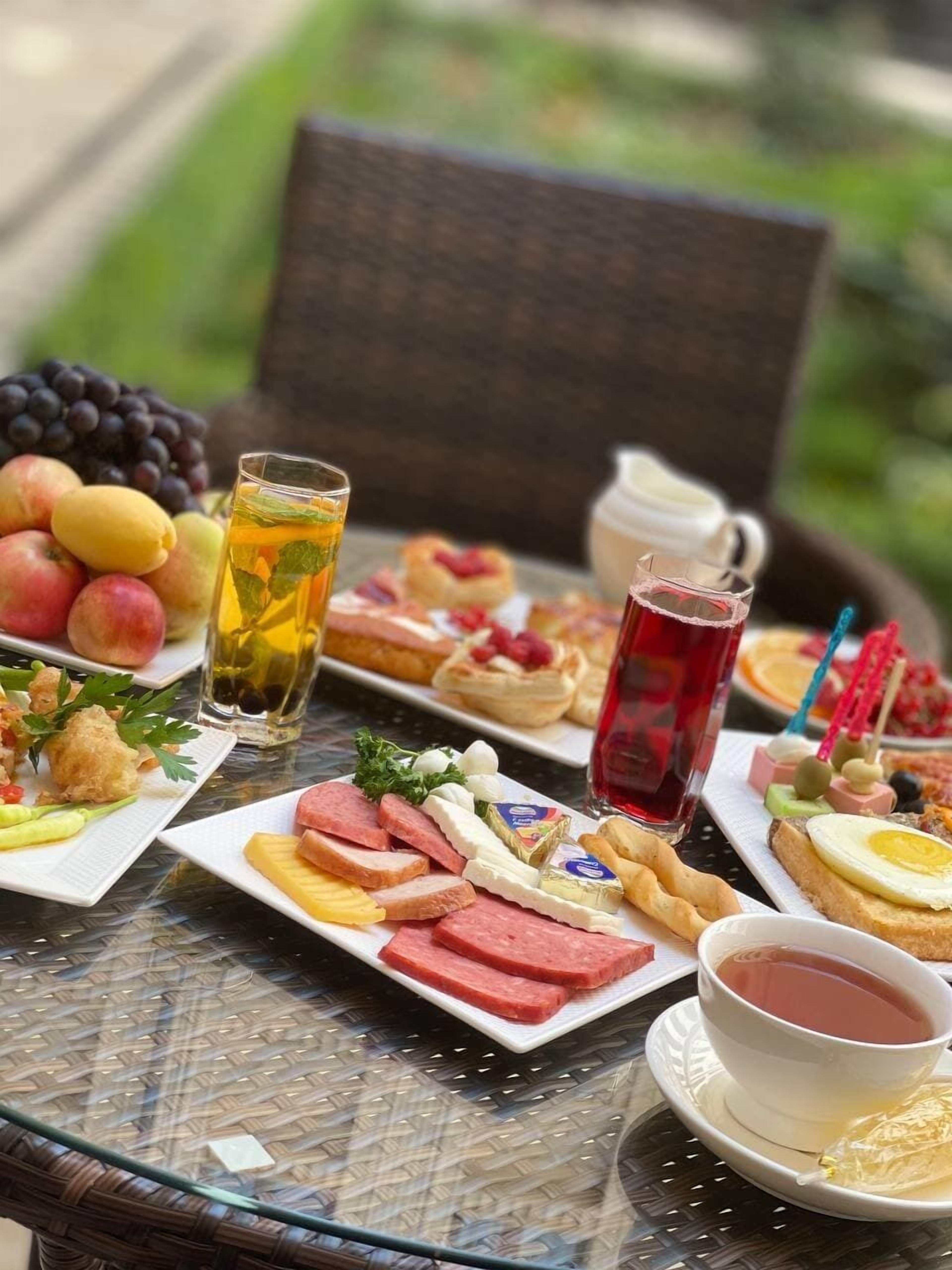 A table set with various foods and drinks, including fruits, cheeses, meats, and beverages.