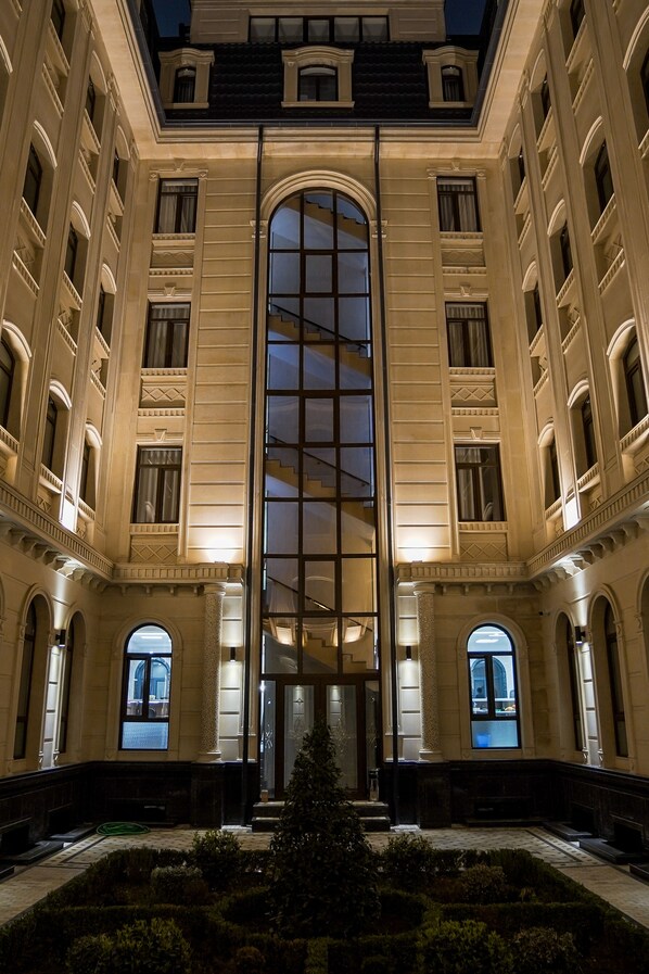 A grand building with a central glass facade, symmetrical architecture, and a formal entrance. - Level Hotel (Tashkent)