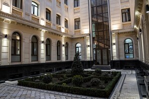 A courtyard with a central tree, surrounded by benches and a tiled floor. - Level Hotel (Tashkent)