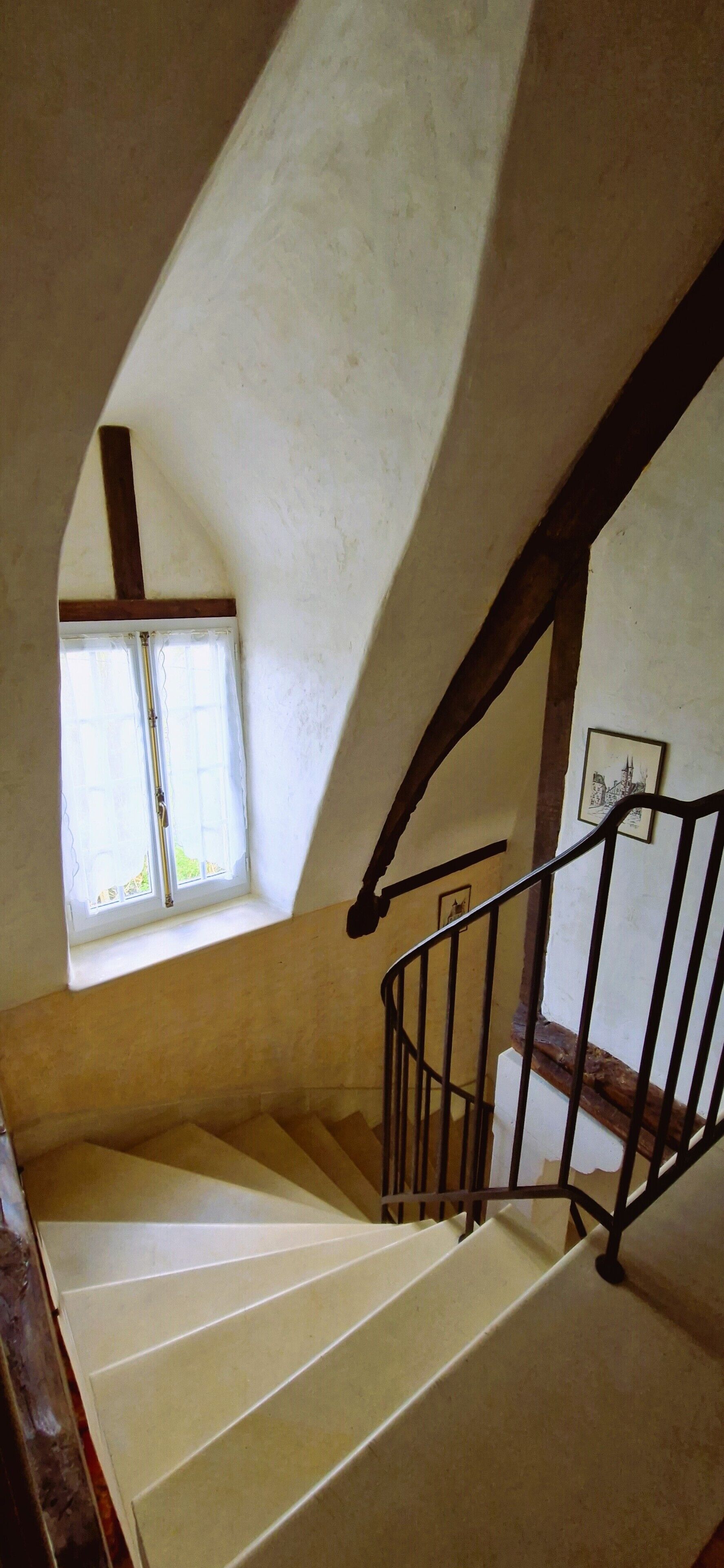 Una escalera con barandilla de madera y una ventana en la parte superior.