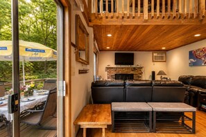 A cozy living area with a fireplace, leather sofa, and a TV mounted on the wall.
