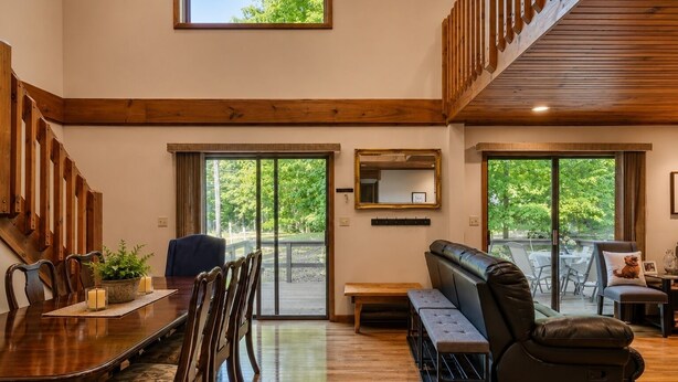 A spacious interior with a dining area, a seating bench, and a view through large glass doors. - Must see the Up Cabin in the Hideout (Lake Ariel)
