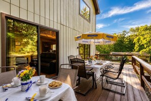 An outdoor dining area with tables and chairs, a wooden deck, and a large umbrella. - Must see the Up Cabin in the Hideout (Lake Ariel)