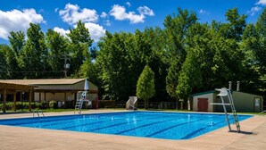 A swimming pool with a lifeguard chair, a covered seating area, and a small building in the background. - Must see the Up Cabin in the Hideout (Lake Ariel)
