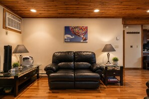 A living room with a leather recliner, a coffee table, a lamp, and a painting on the wall.