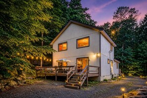 A two-story wooden building with a porch, outdoor seating, and a staircase leading to the entrance.