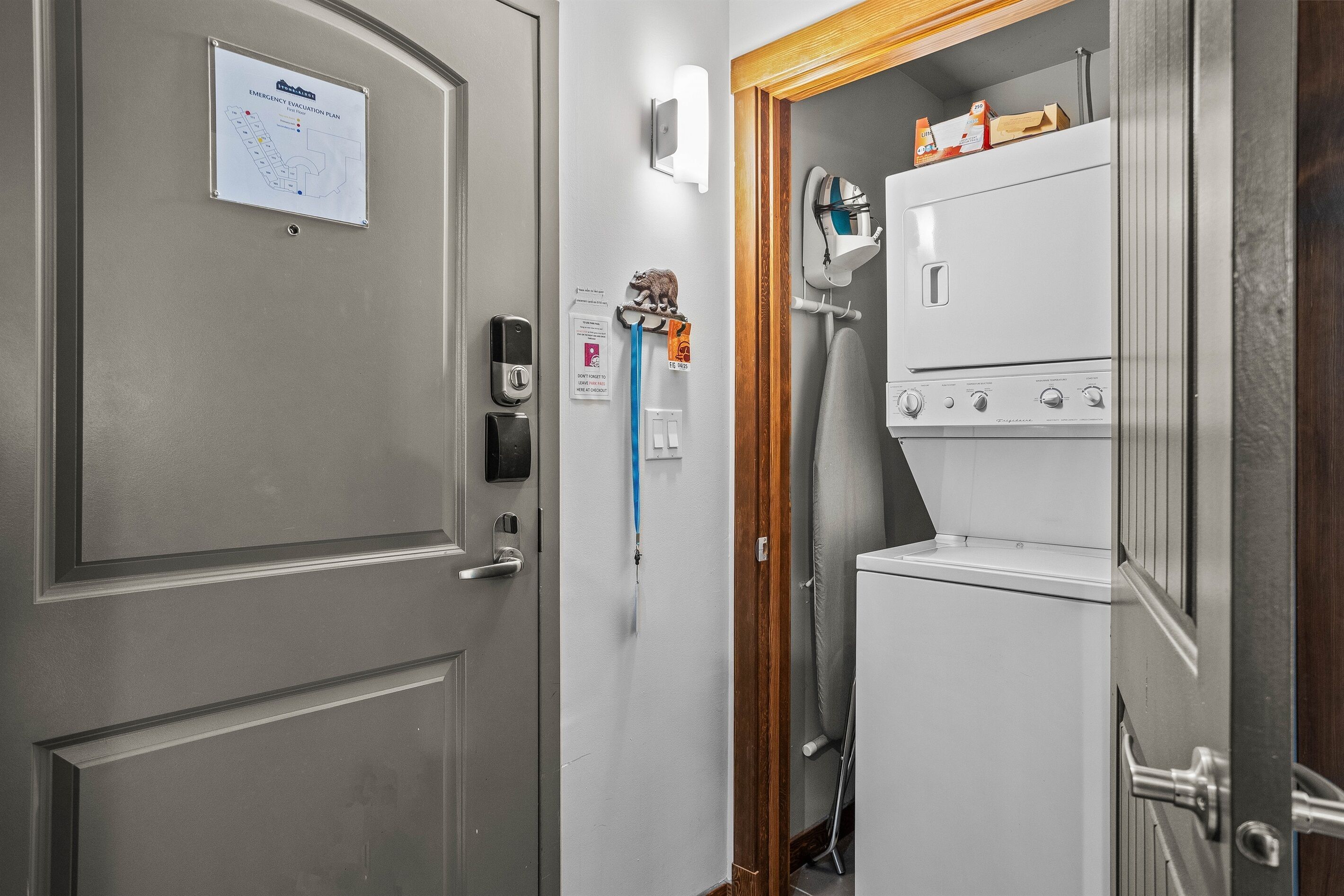 A hotel room with a door, a wall-mounted emergency evacuation plan, a towel rack with a towel and a small decorative item, and a washing machine.