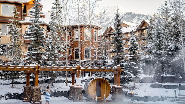 Une station de ski enneigée avec des bâtiments en bois, un sauna en bois et un espace dédié aux sources chaudes.