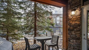 Une terrasse extérieure avec un mur en pierre, une table et deux chaises.