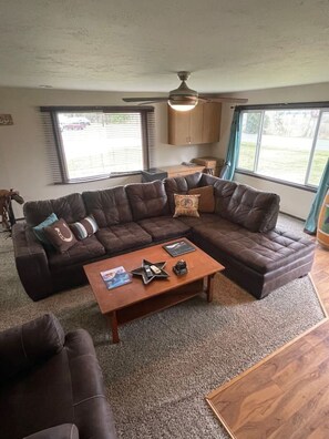 A living room with a sectional sofa, a coffee table, and a ceiling fan. - The Cowboy cottage  (Bellingham)