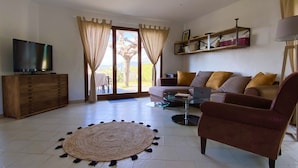 A living room with a sofa, armchair, coffee table, TV, and a view through the glass door. - House Agosta plage- Terrace with sea view - Sea 500m - 10 people (Albitreccia)