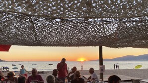 A beachside restaurant with outdoor seating under a canopy, overlooking the sea and a sunset. - House Agosta plage- Terrace with sea view - Sea 500m - 10 people (Albitreccia)