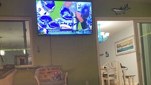 A living room with a flat-screen TV mounted on the wall, a fireplace, and a sign on the wall.