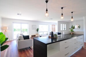 A modern kitchen with a central island, pendant lighting, and large windows providing natural light. - Beach Haven - Modern home located right in town, you wont get better. (Robe)