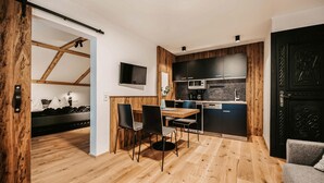 A modern kitchen with wooden accents, a dining area with two chairs, and a black door. - schoene Ferienwohnung-Wagrain (Wagrain)