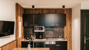 A compact kitchen with dark cabinets, a microwave, a coffee maker, and a dishwasher. - schoene Ferienwohnung-Wagrain (Wagrain)