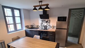 Una cocina moderna con zona de comedor. Incluye una mesa de madera, cuatro sillas, un fregadero, una estufa y un refrigerador.