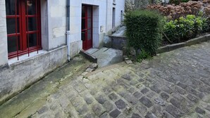 Un patio con pavimento de piedra, un edificio con marcos de ventana rojos y una torre.