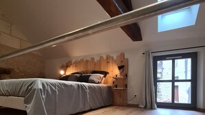 Un dormitorio con cama, cabecero de madera y tragaluz.