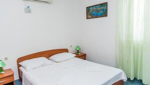 A neatly made bed with white linens, a wooden headboard, a green lamp on a bedside table, and a painting on the wall. - Beautiful apartment in Slatine with WiFi (Slatine)