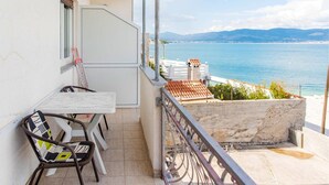 A balcony with a table and chairs, overlooking a coastal view with a clear sky and distant mountains. - Beautiful apartment in Slatine with WiFi (Slatine)
