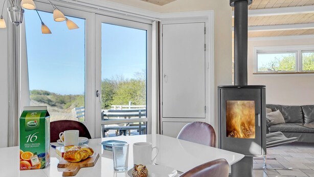 Een moderne kamer met een groot raam, een tafel met ontbijtartikelen en een houtkachel.