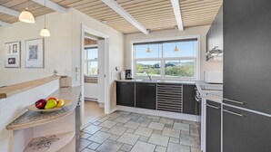 Een moderne keuken met een groot raam, een inbouwoven en een aanrecht met fruit.