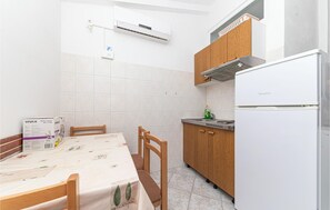 Eine kompakte Küche mit einem weißen Kühlschrank, Holzschränken und einer gefliesten Spritzschutzwand.