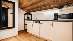 Une cuisine moderne avec des poutres en bois au plafond, un four à micro-ondes, une machine à café et une étagère contenant de la verrerie.