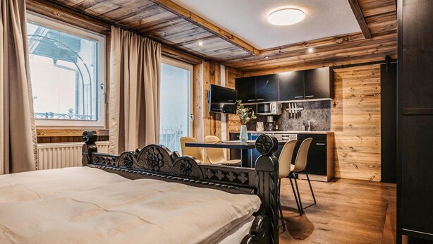 Un dormitorio con cama, escritorio y kitchenette.