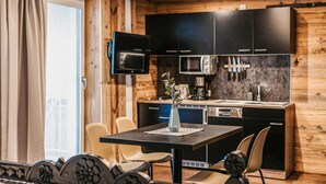 Una cocina moderna con armarios negros, un televisor de pantalla plana y un comedor con mesa y sillas.