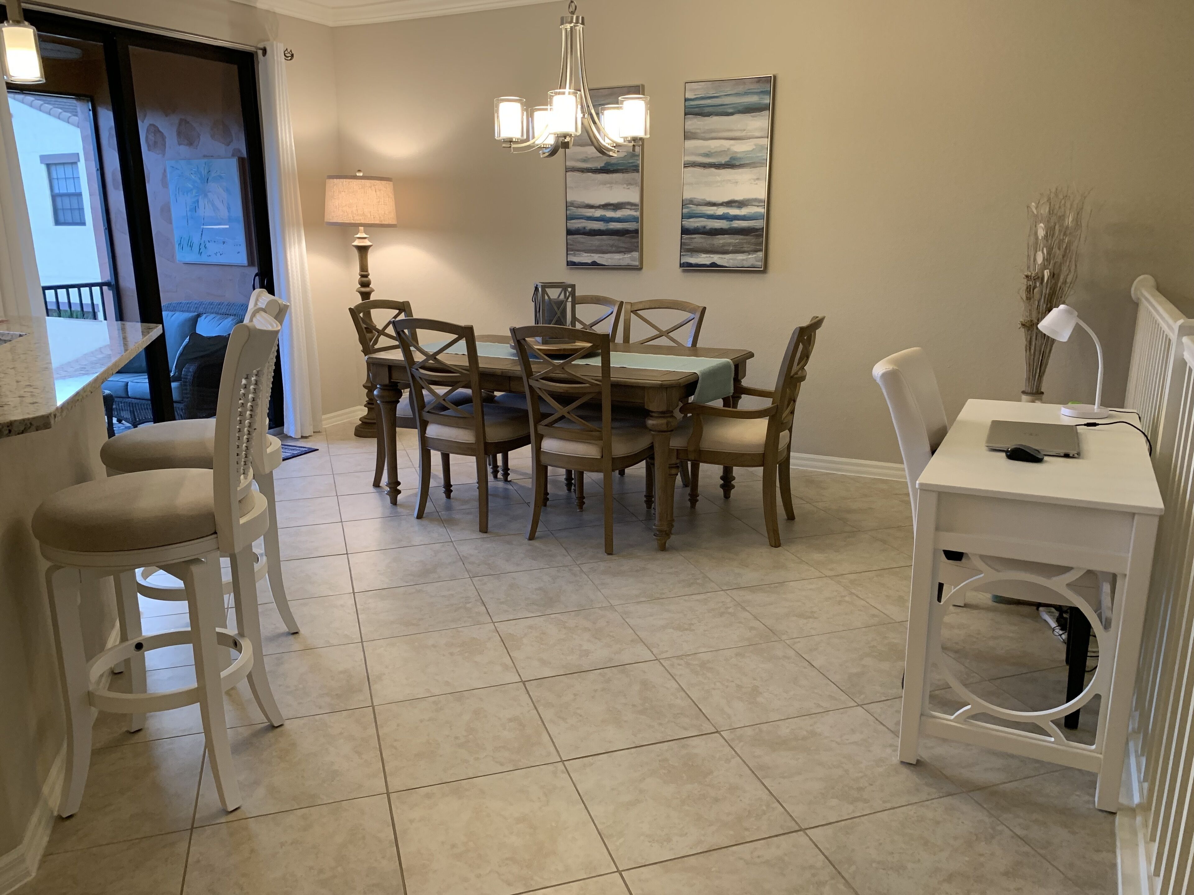 A dining area with a wooden table and chairs, a chandelier, and artwork on the wall.