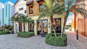 A hotel entrance with a modern design, palm trees, and a paved walkway. - Beautiful 3 BR 2.5 Bath Paseo Townhome in a Quad (Fort Myers)