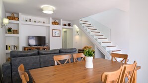 A modern living room with a wooden dining table, grey sofa, and a staircase. - Casa Grumete, moderno y actual (Playa Honda)
