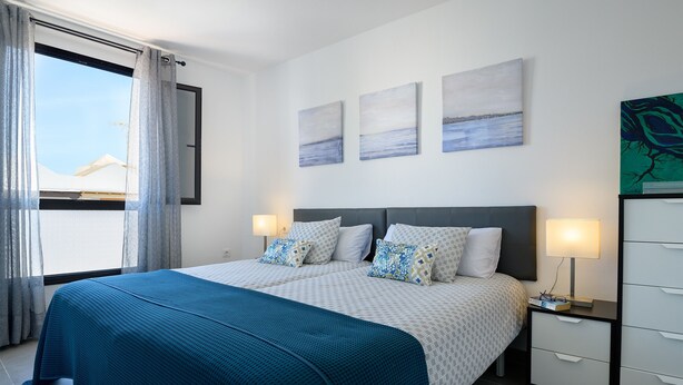 A neatly arranged bedroom with a large bed, two bedside tables, and a nightstand. - Casa Grumete, moderno y actual (Playa Honda)
