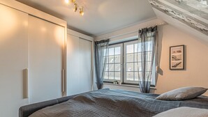 A bedroom with a bed, a wardrobe, a window with curtains, and a framed picture on the wall. - 2 bedroom beautiful apartment in Friedrichskoog (Friedrichskoog)