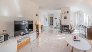 A modern living room with a flat-screen TV, a fireplace, and a dining area with a table and chairs. - 2 bedroom beautiful apartment in Friedrichskoog (Friedrichskoog)