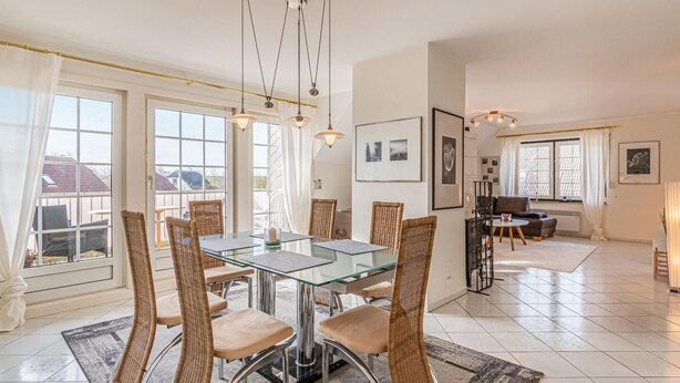 A spacious dining area with a glass table and wicker chairs, a cozy living room with a sofa and a coffee table, and large windows with curtains. - 2 bedroom beautiful apartment in Friedrichskoog (Friedrichskoog)