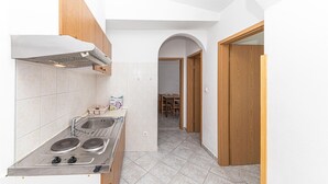 Una cocina compacta con estufa a gas, lavamanos y armarios de madera.