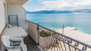 Un balcón con vista a un mar tranquilo y montañas lejanas.