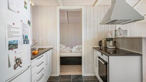 Eine kleine Küche mit Holzausstattung, einem eingebauten Backofen und einer Kaffeemaschine auf der Arbeitsfläche.