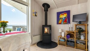 Ein gemütliches Zimmer mit Kaminofen, Fernseher und einem Bild an der Wand.