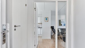 A modern interior with a white door, a kitchen area, and a seating area with a sofa and chairs. - Gorgeous home in Tranekær with kitchen (Tranekær)