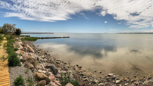 A calm lake with a wooden boardwalk and rocky shoreline.
