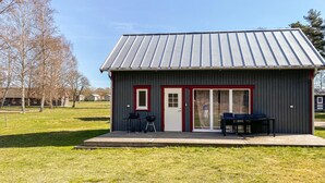 A small, single-story building with a metal roof, a front door, and a sliding glass door.