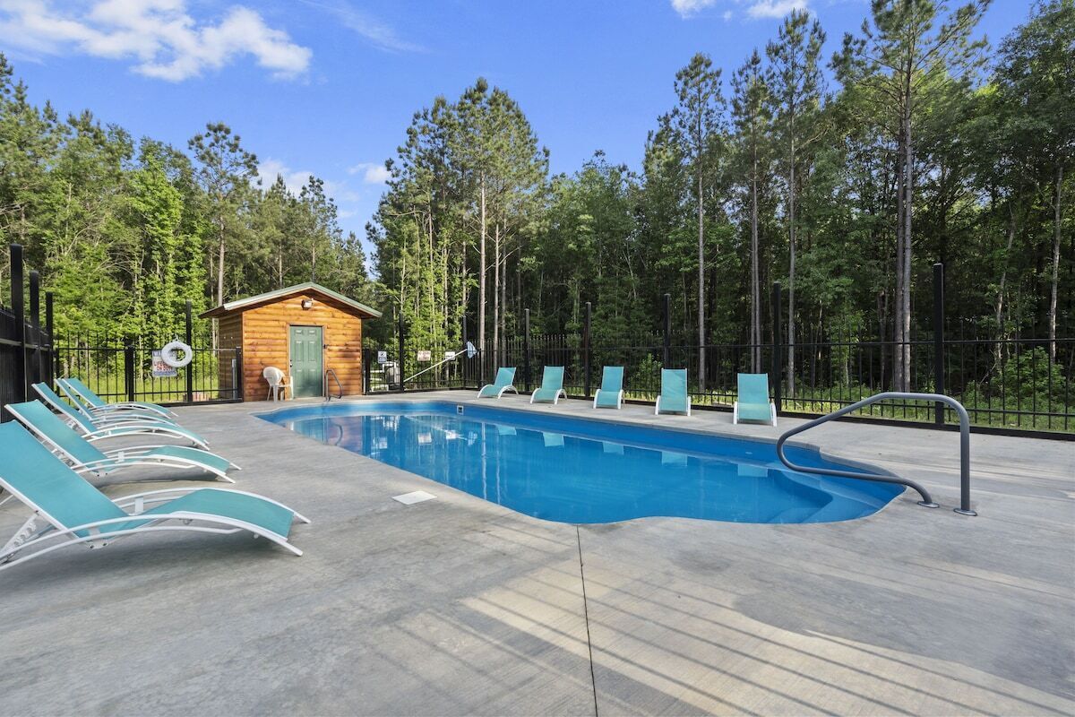 A swimming pool with lounge chairs and a small wooden cabin.